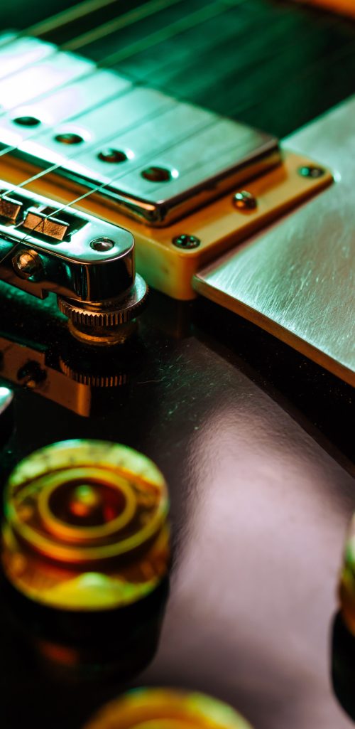 Macro abstract photo of the pickups, bridge and knobs of an electric guitar. Shallow depth of field with focus across the middle.